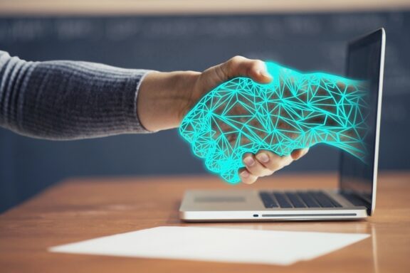 man shaking digital hand coming out of computer screen