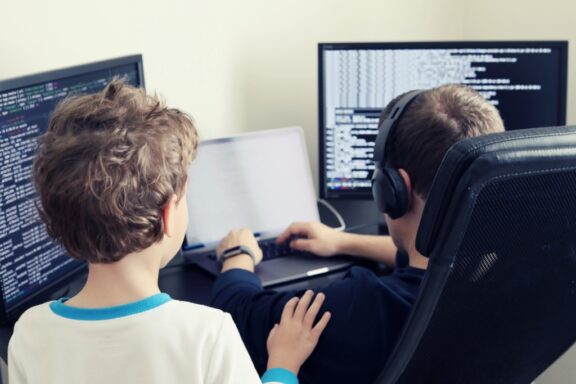 dad teaching son how to code on his computer
